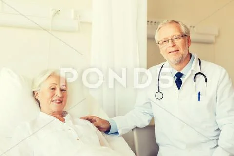 Doctor visiting senior woman at hospital ward Stock Photos