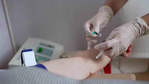 A doctor wearing gloves inserts a needle into a patient's vein. Stock Footage 255515031