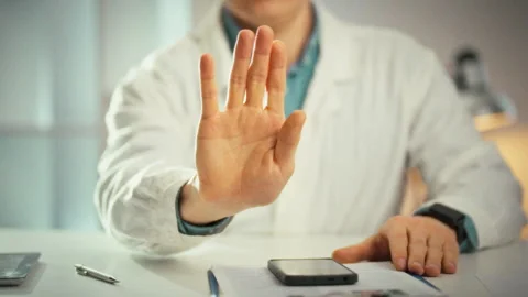 A doctor in a white coat extends a hand palm outward signaling stop in a clo Stock Footage 333501091