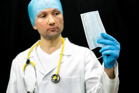 A doctor in a white coat holds a white medical mask in his hand. Gauze bandag Stock Photos