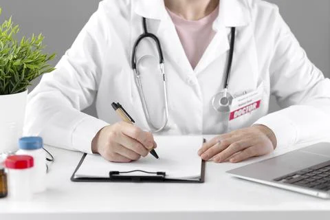 A doctor in a white coat makes a note on paper with a pen. Stock Photos