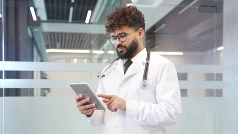 Doctor in white coat using digital tablet standing in modern hospital office.  Stock Footage 321820731