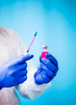 A doctor in a white virus-protected suit and blue medical rubber gloves is dr Stock Photos