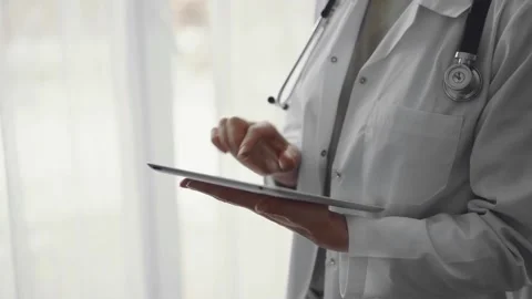 Doctor woman at work using tablet computer while standing near panorama window Stock Footage 243074061
