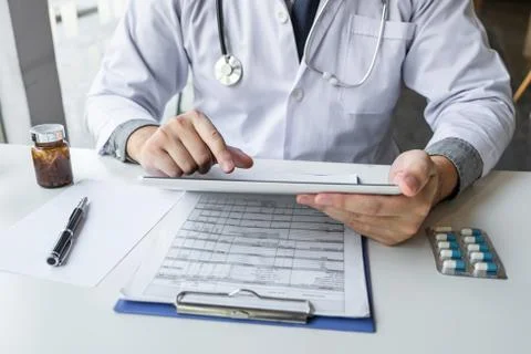 Doctor working and using digital tablet note information on paper report in h Stock Photos