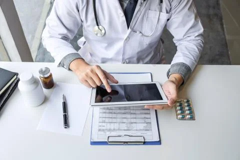 Doctor working and using digital tablet note information on paper report in h Stock Photos