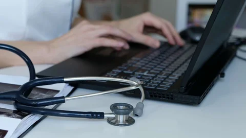 Doctor working on a computer, keyboard close up. Stethoscope on a table Stock Footage 129333199