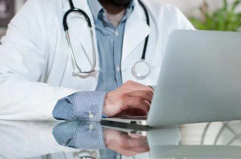 Doctor working on desk with laptop computer in doctors office. Medical, docto Stock-Fotos