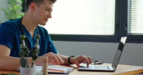 Doctor working with laptop computer and writing on paperwork. Stock Footage 279403816