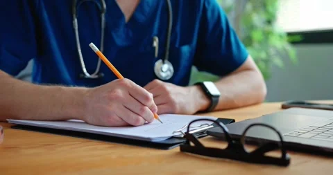 Doctor working with laptop computer and writing on paperwork. Stock Footage 279404663