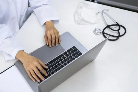 Doctor working with laptop computer sitting at desk in hospital office or c.. Фото