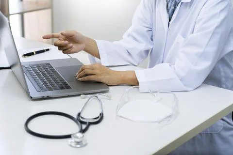 Doctor working with laptop computer sitting at desk in hospital office or c.. Фото