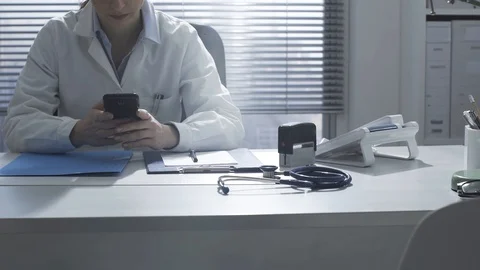 Doctor working in the office and using a smartphone Stock Footage 117922323