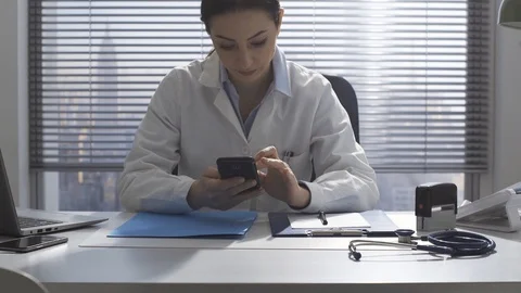 Doctor working in the office and using a smartphone Stock Footage 127364885