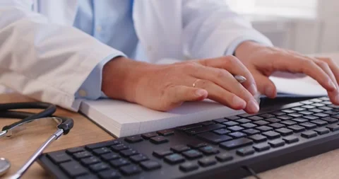 Doctor working in office typing on pc computer and writing in notepad in medical Stock Footage 320551046
