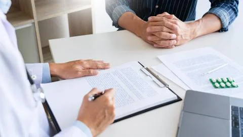 Doctor working with patient taking notes with clipboard and discussing someth Foto stock