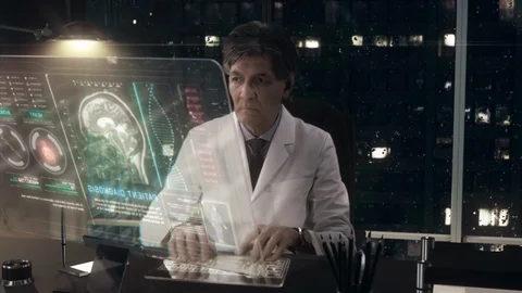 Doctor working on a Transparent Display Computer at his office at night. Video stock 107952287