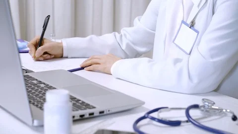 The doctor works on a computer writing notes in a document. Stock-Footage 124599186