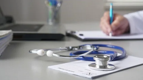 Doctor Writing A Document In The Consulting Room Stock Footage 75579008