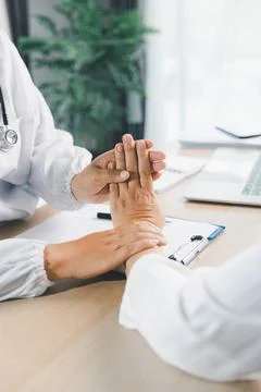 Doctor writing medical notes while patient explains symptoms with hand gest.. Stock Photos