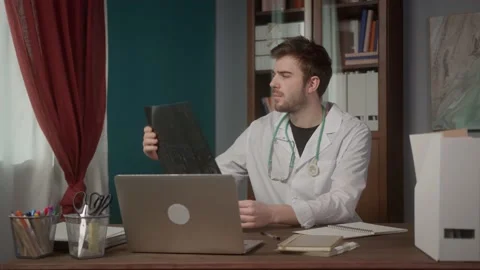 Doctor writing notes, looking at x-ray, consultation Video Conference in Medical Stock Footage 155353333