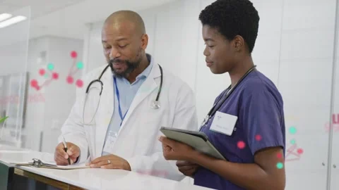 Doctor writing notes nurse station, starting color dots linking notes to tablet Stock Footage 333485897