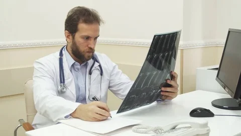 The doctor is writing a recommendations after checking the X-Ray Stock Footage 80288152