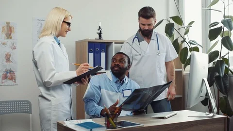 Doctors and interns looking closely at X ray. Three health care workers in Stock Footage 91334281