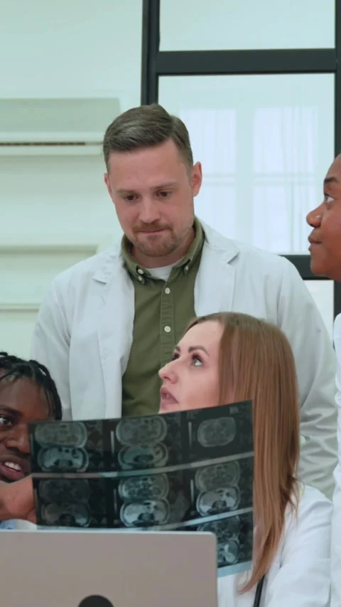 Doctors and nurses examine a brain x-ray scan on a laptop, engaging Stock Footage 313375346
