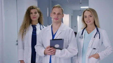Doctors are looking into the camera standing in the corridor of the hospital Stock Footage 224056812