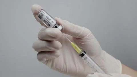 Doctors are preparing a Covid-19 vaccine from a small bottle and syringe. Stock Footage 135524658