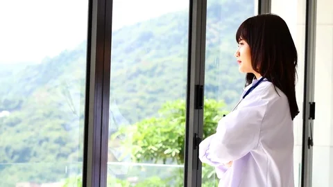 Doctors are standing looking through the window and thinking of something. 動画素材 79609592