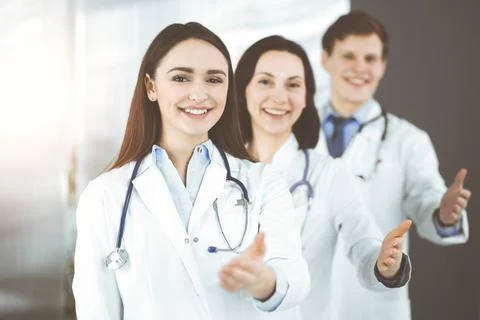 Doctors are standing as a team while offering their helping hands for shaking Stockfoto's