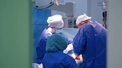 Doctors in blue uniform doing a surgery in clinic. Stock Footage 125895204