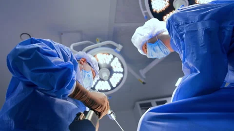 Doctors in blue uniforms stand close to each other under the round lamps. Low Stock Footage 342572698