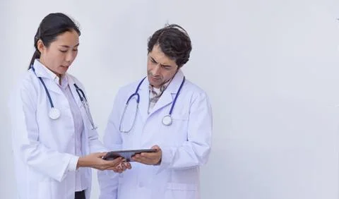 Doctors checking patient information on a tablet device Stock Photos