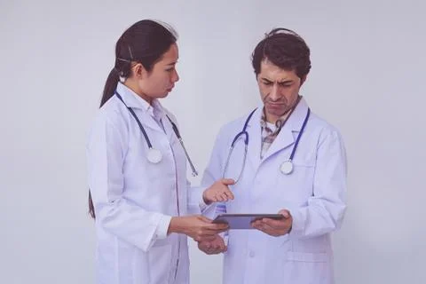 Doctors checking patient information on a tablet device Stock Photos