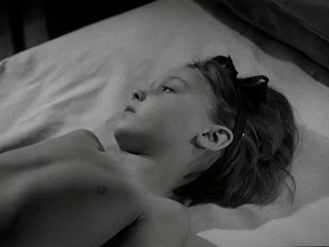 Doctors checking up on young ill girl, talking about advancing disease, UK 1947 Video stock 134033797