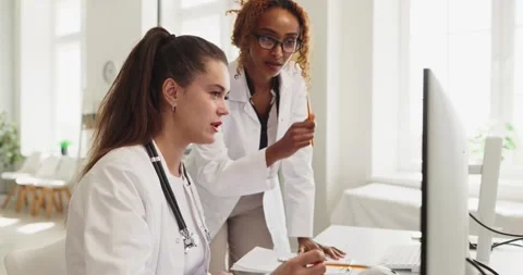 Doctors collaborating at computer in clinic, reviewing patient records and Stock Footage 336006550