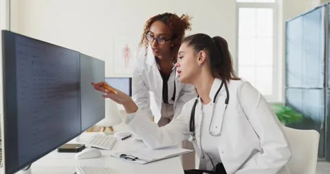 Doctors collaborating at computer to review patient records and plan clinical Stock Footage 336123886