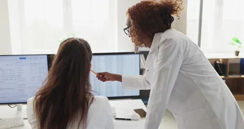 Doctors collaborating at computer workstation reviewing patient records and Stock Footage 336097901