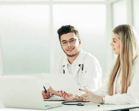 Doctors colleagues talking sitting at a table in the office Stock Photos