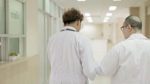 Doctors discussing data on a computer tablet as they stroll down a hospital c Stock Footage 164760428
