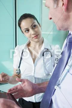 Doctors Discussing Medical Records On Digital Tablet