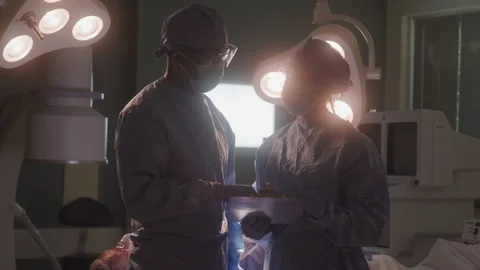 Doctors Exchanging Notes In Operating Room Stock Footage 211881077