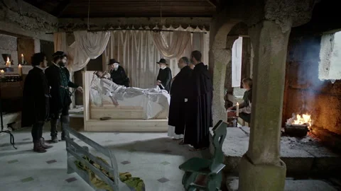 Doctors gather around a bed to check on a patient in a medieval room Stock Footage 327950416