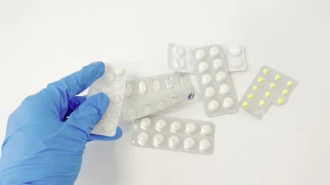 Doctor's gloved hand holding blister packs and dispensing white pills for m.. Stock Footage 335141507