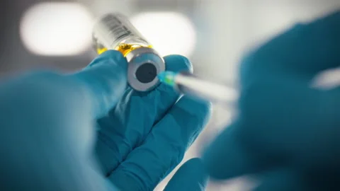 A doctors gloved hands carefully prepare a syringe by piercing a sealed medi Stock Footage 331312421