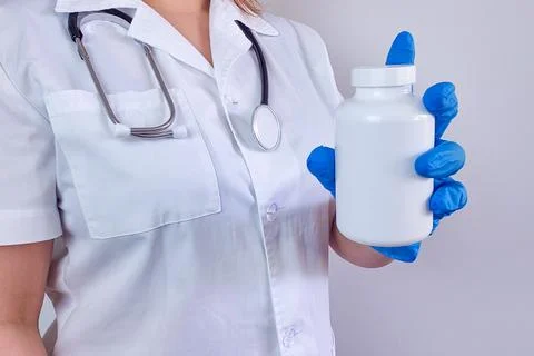 Doctor's gloved hands holding a bottle of pills close-up, medications, bann.. Stock Photos