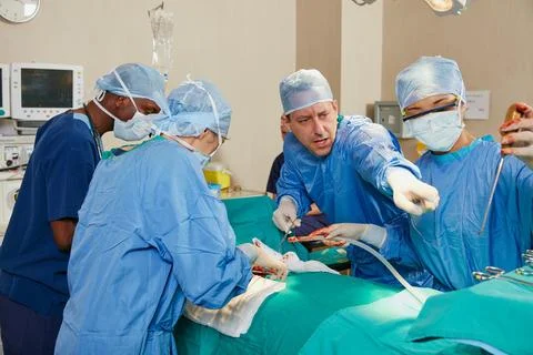 Doctors, group and man pointing in theater with surgery tools for healthcar.. Stock Photos